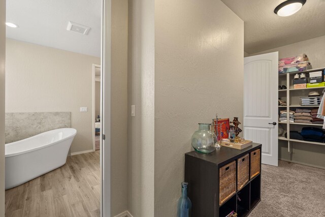 bathroom featuring a tub to relax in, vanity, hardwood / wood-style floors, and a textured ceiling