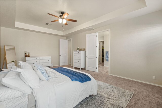 carpeted bedroom with ceiling fan and a tray ceiling