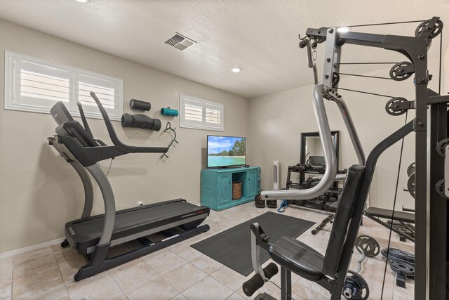 workout room with light tile patterned floors and a textured ceiling