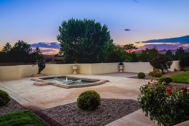 pool at dusk with a patio area