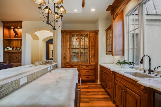 interior space with light stone counters, dark wood-type flooring, sink, pendant lighting, and a chandelier