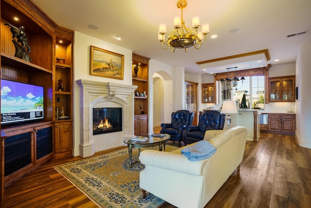 living room with dark wood-type flooring, built in features, and a notable chandelier