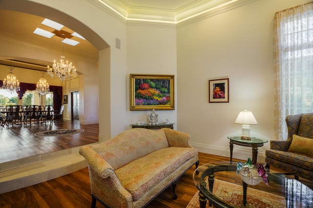 living room featuring crown molding, dark wood-type flooring, and an inviting chandelier