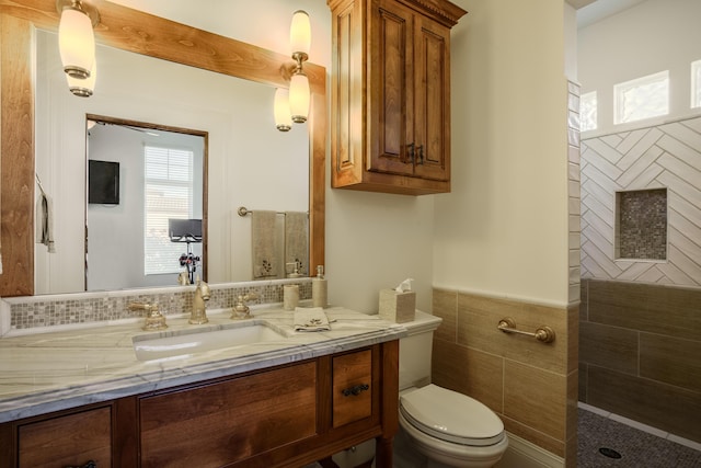 bathroom featuring vanity, tile walls, and toilet