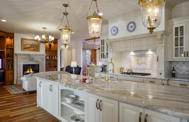 kitchen with white cabinets, stainless steel gas stovetop, hanging light fixtures, and tasteful backsplash