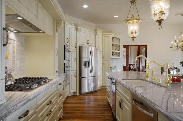 kitchen with light stone countertops, sink, decorative light fixtures, and appliances with stainless steel finishes