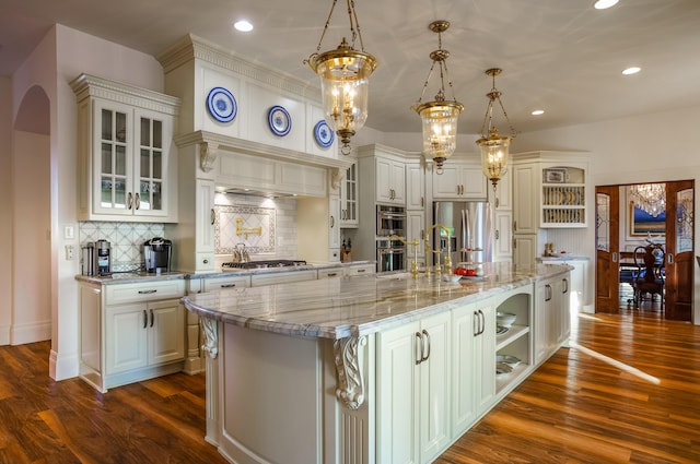 kitchen featuring backsplash, an island with sink, decorative light fixtures, and appliances with stainless steel finishes