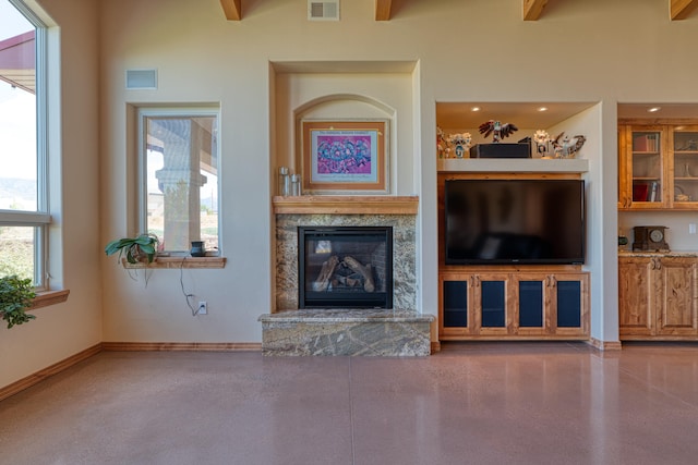 unfurnished living room with a fireplace, beam ceiling, and a towering ceiling