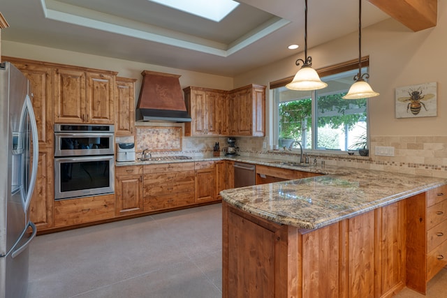 kitchen with light stone countertops, kitchen peninsula, backsplash, premium range hood, and stainless steel appliances