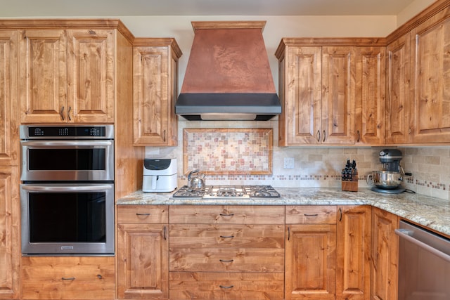 kitchen featuring custom exhaust hood, light stone countertops, stainless steel appliances, and tasteful backsplash