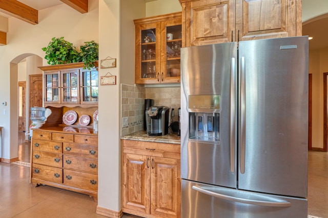 kitchen with beamed ceiling, stainless steel fridge, tasteful backsplash, and light stone countertops