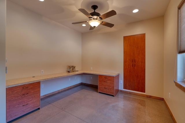 unfurnished office featuring built in desk and ceiling fan