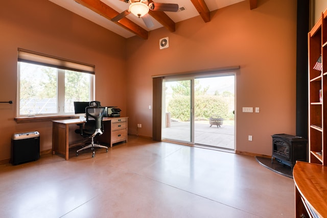 office area featuring beam ceiling, a wood stove, and ceiling fan