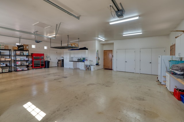 garage with white refrigerator, a garage door opener, and sink