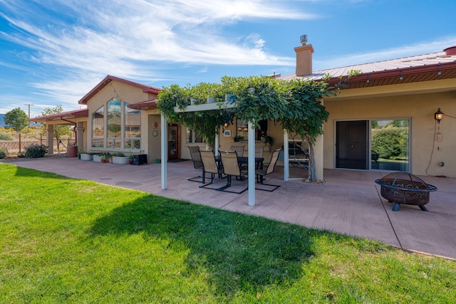 rear view of property with a patio area, a yard, and an outdoor fire pit