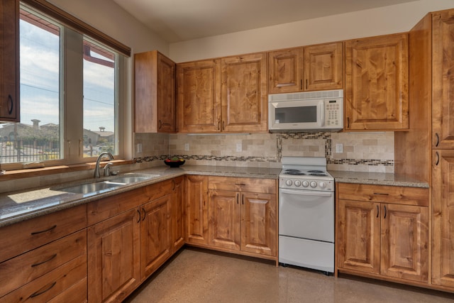 kitchen with white appliances, sink, stone counters, and tasteful backsplash