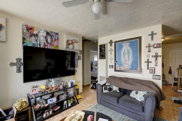 living room with ceiling fan, light tile patterned floors, and a textured ceiling