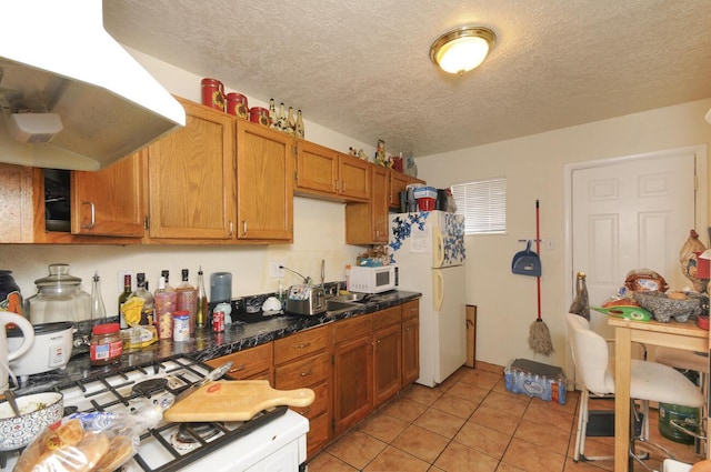 kitchen featuring light tile patterned floors, exhaust hood, white appliances, and a textured ceiling