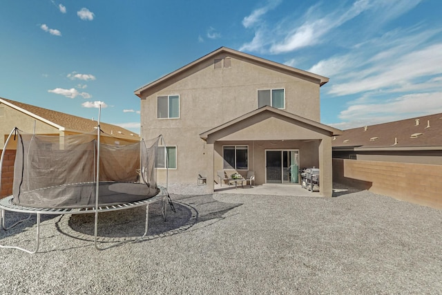 back of property with a trampoline and a patio