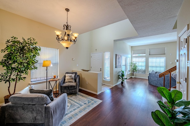 living area with an inviting chandelier, dark hardwood / wood-style floors, and a textured ceiling