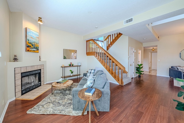 living room with hardwood / wood-style floors and a tiled fireplace