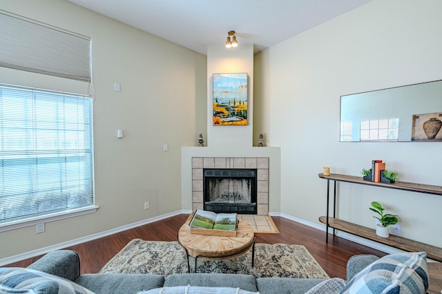 living room with a tile fireplace and dark hardwood / wood-style floors