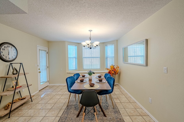 tiled dining area with plenty of natural light, an inviting chandelier, and a textured ceiling