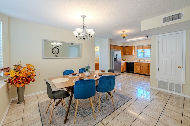 tiled dining space with sink, an inviting chandelier, and a textured ceiling