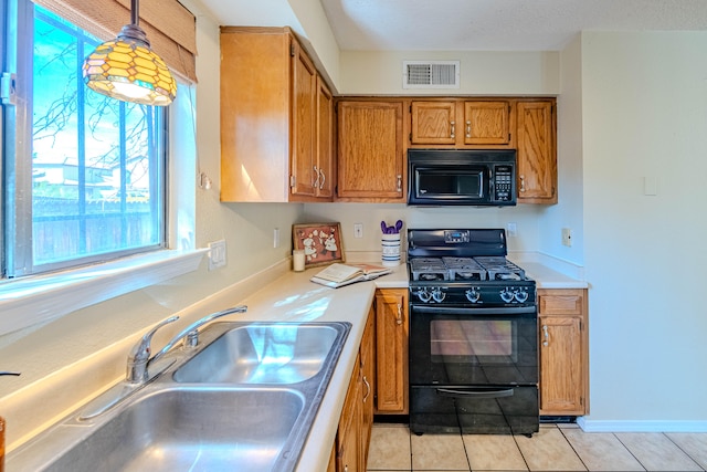 kitchen featuring pendant lighting, light tile patterned flooring, sink, and black appliances