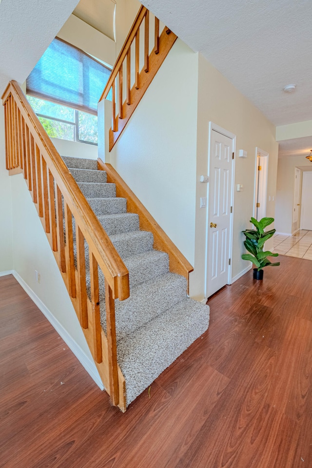 staircase featuring wood-type flooring and a textured ceiling