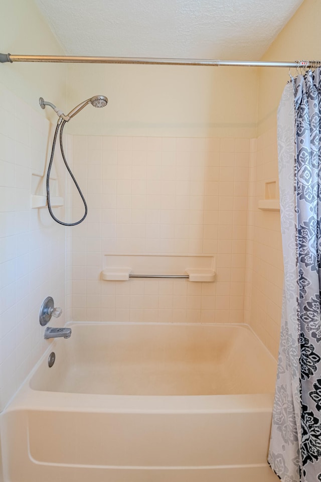 bathroom featuring a textured ceiling and shower / bathtub combination with curtain