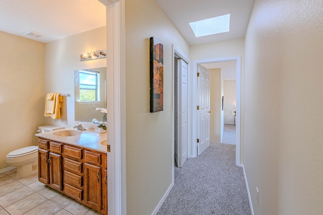 corridor featuring a skylight, sink, and light colored carpet