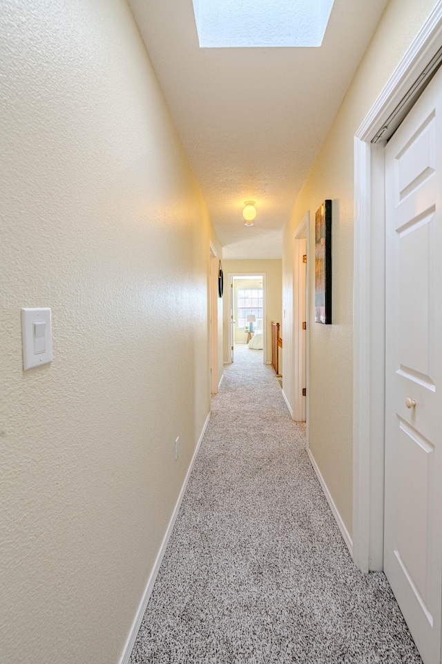 hall featuring a skylight and light colored carpet