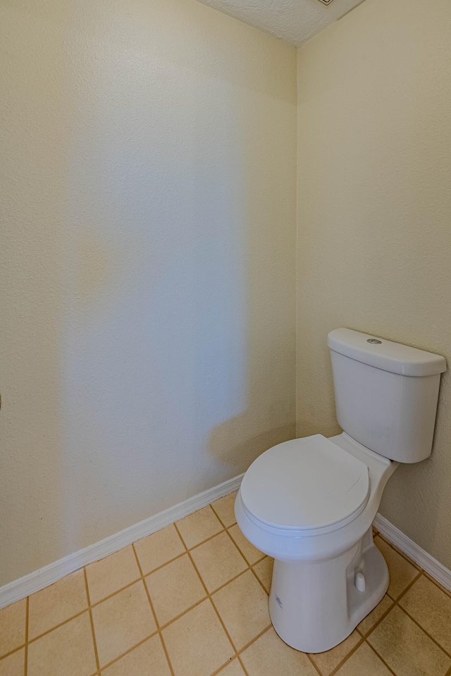 bathroom featuring a textured ceiling, toilet, and tile patterned floors