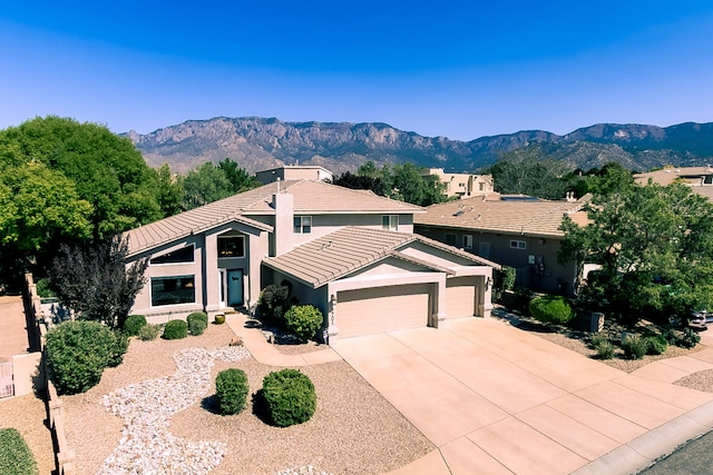 view of front of property with a tile roof, a mountain view, driveway, an attached garage, and stucco siding