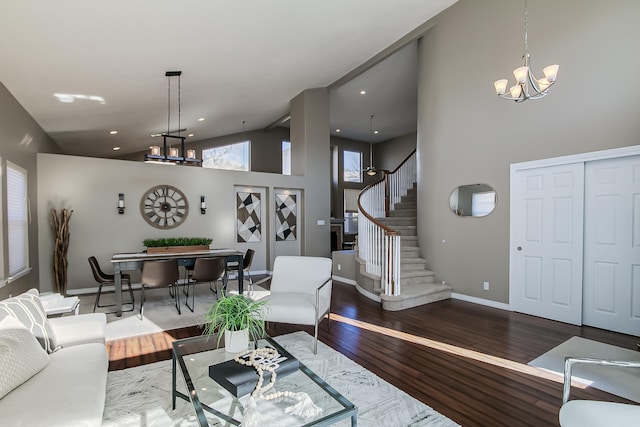 living room with wood-type flooring, a towering ceiling, and a notable chandelier