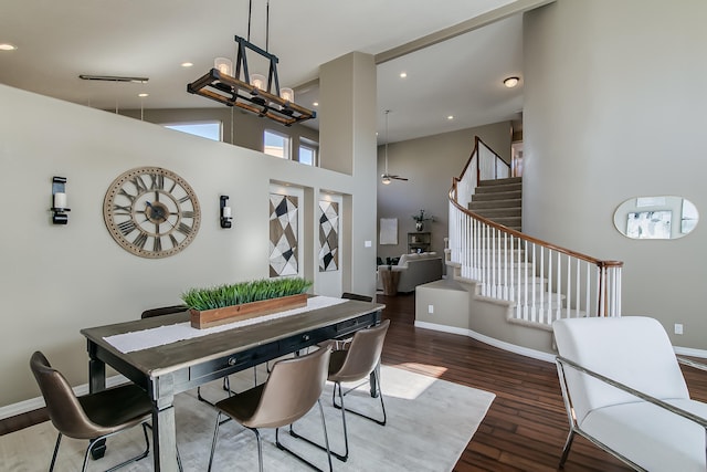 dining space with ceiling fan, a towering ceiling, and dark hardwood / wood-style floors