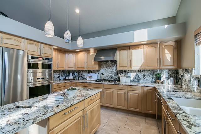 kitchen with light tile patterned flooring, decorative backsplash, wall chimney range hood, light stone countertops, and appliances with stainless steel finishes