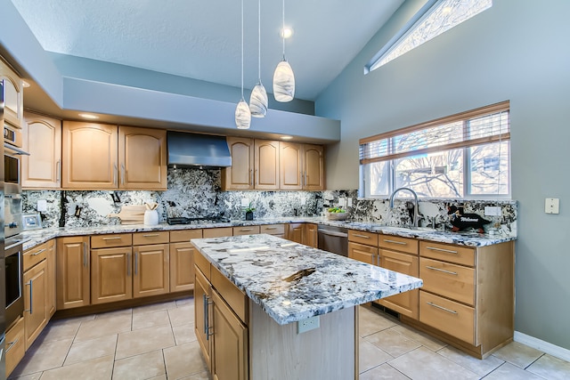 kitchen with wall chimney exhaust hood, sink, light tile patterned floors, a kitchen island, and hanging light fixtures