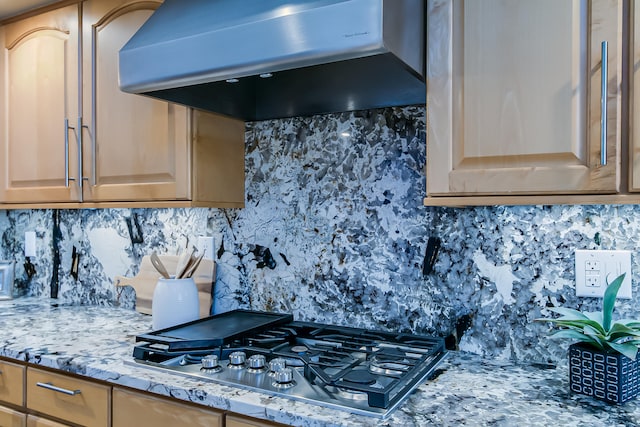 kitchen featuring stainless steel gas stovetop, decorative backsplash, light stone countertops, and extractor fan