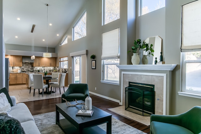 living room with a tile fireplace, a high ceiling, and wood-type flooring