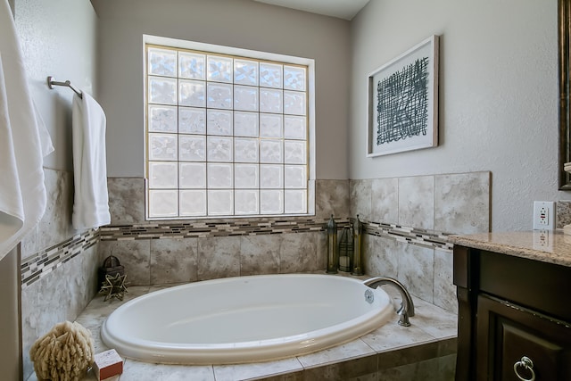 bathroom featuring vanity and a relaxing tiled tub