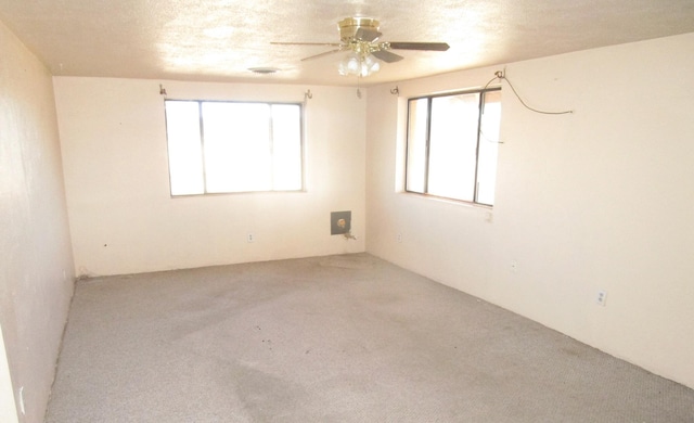 empty room featuring a textured ceiling, a wealth of natural light, and ceiling fan