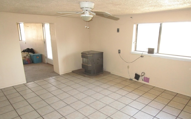 spare room with a wood stove, ceiling fan, and a textured ceiling