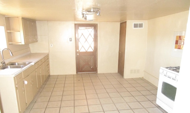 kitchen with light tile patterned floors, gas range gas stove, and sink