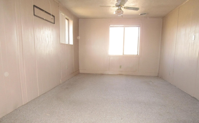 carpeted empty room with ceiling fan and wood walls