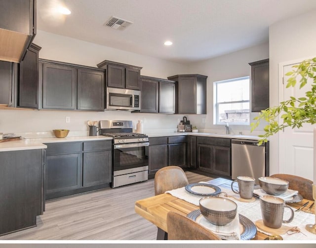 kitchen featuring stainless steel appliances, light hardwood / wood-style floors, sink, and dark brown cabinets