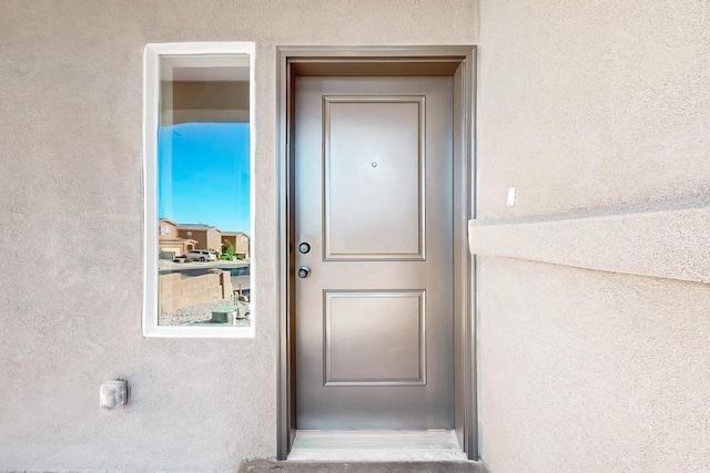 doorway to property featuring stucco siding