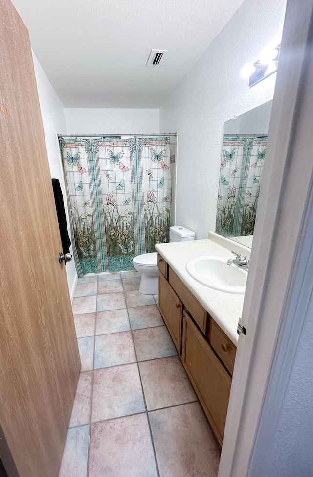 bathroom with curtained shower, a textured ceiling, toilet, tile patterned floors, and vanity