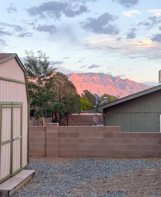 yard at dusk featuring a storage unit and a mountain view